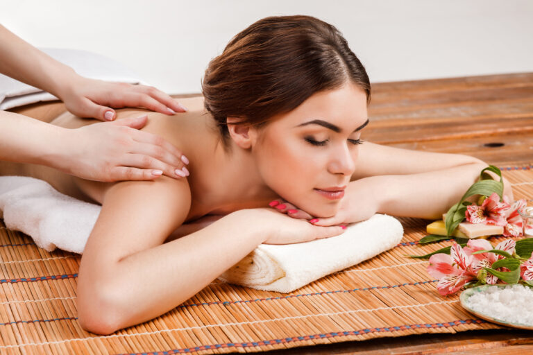 Beautiful young woman at a spa salon resting on a straw mat. Concept of body care and relaxation