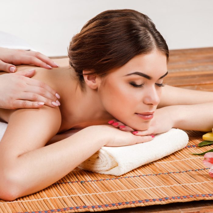 Beautiful young woman at a spa salon resting on a straw mat. Concept of body care and relaxation